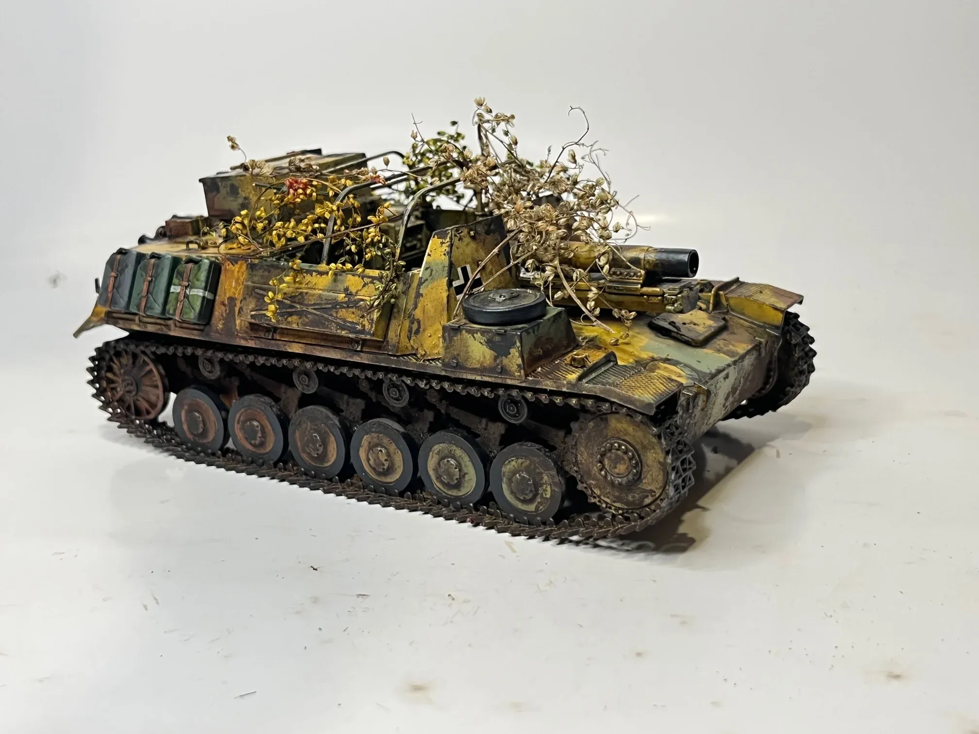 Maquette d’un char couvert de branchages et de paquetages, camouflage jaune et vert