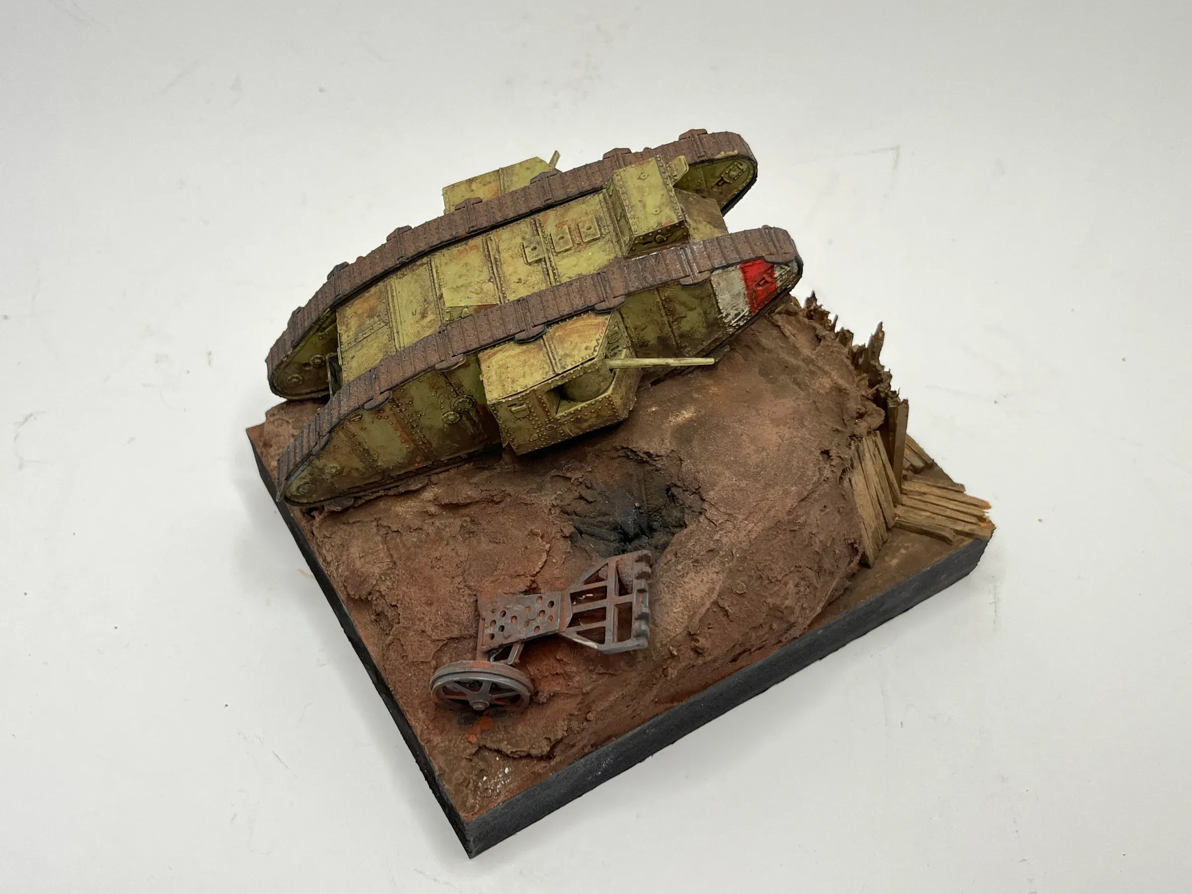 Diorama : un char britannique de la Première Guerre mondiale, en forme de losange, franchit une tranchée boueuse