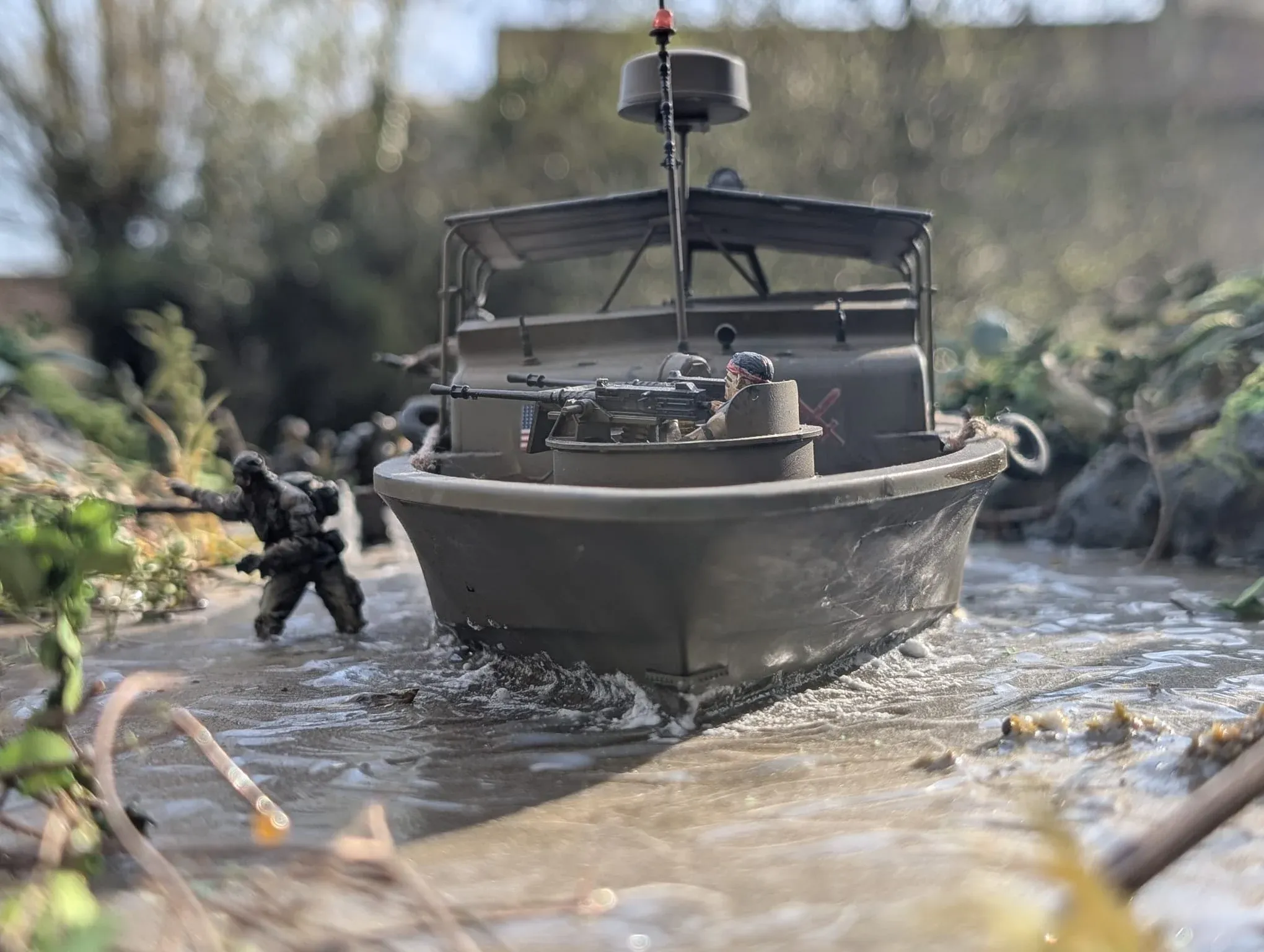 Diorama photographié en extérieur : un patrouilleur fluvial remonte une rivière dans la jungle