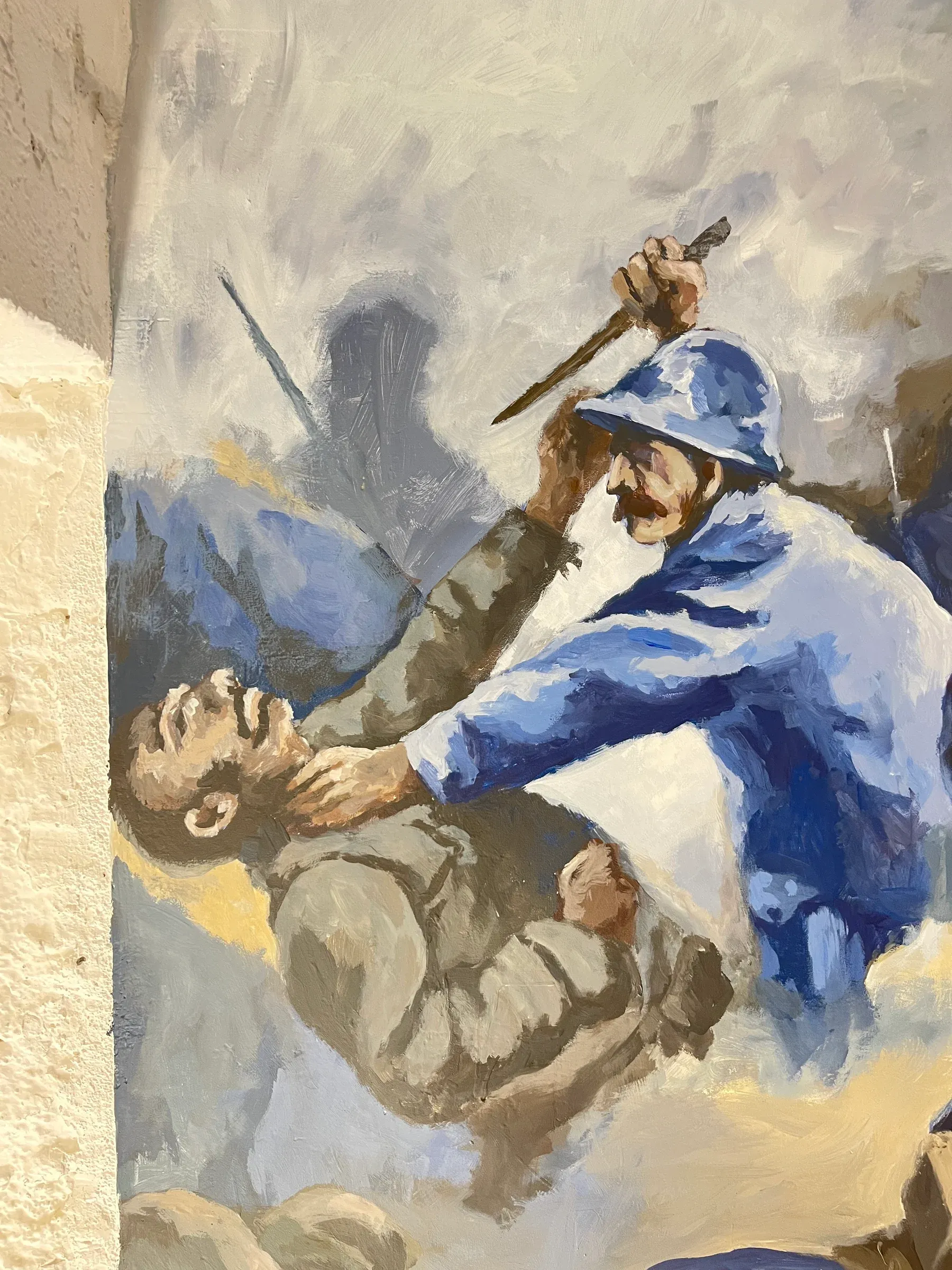 Détail de la fresque : un soldat casqué, en bleu horizon, lève son couteau au-dessus d’un adversaire à terre